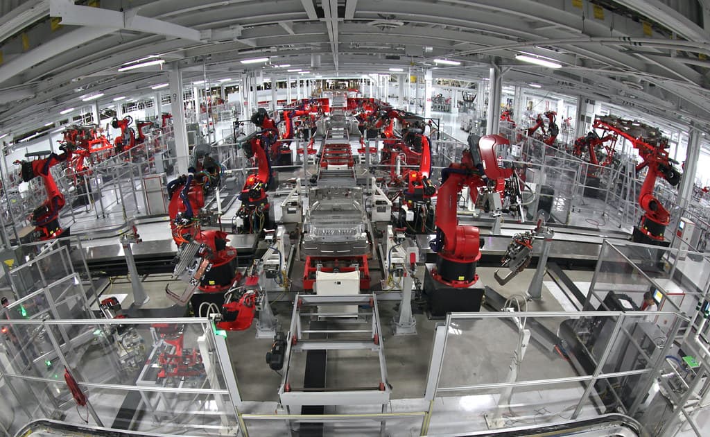 Industrial robot arms along a car assembly line.