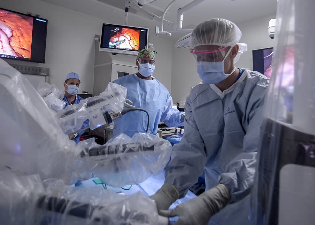 Surgeons working at a robotic surgical system in an operating room.